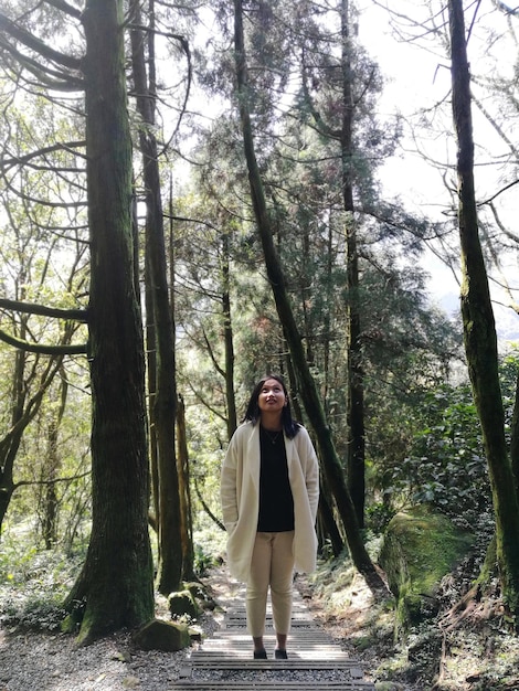 Une jeune femme levant les yeux alors qu'elle se tient sur un sentier dans la forêt