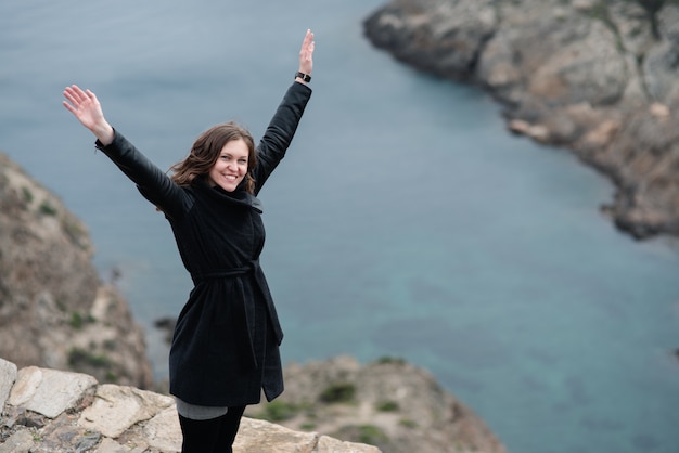 jeune femme lève les bras vers le ciel en signe de liberté et de succès