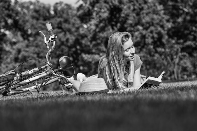 Jeune femme lisant un livre après avoir fait du vélo dans le parc local