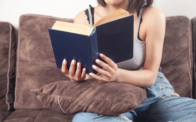 Jeune femme lisant un livre assis sur un canapé