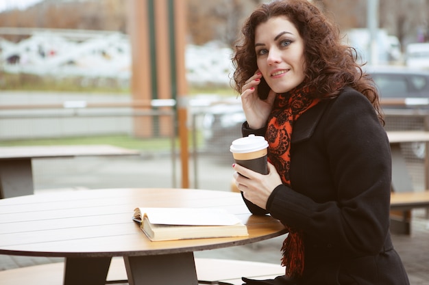 Jeune femme lisant un livre dans un café de la rue