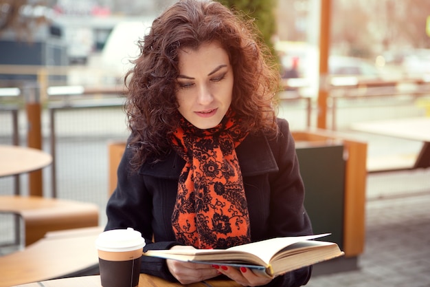 Jeune femme lisant un livre dans un café