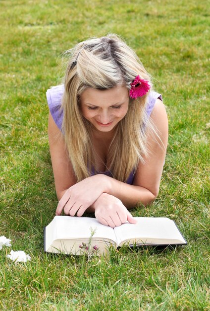 Jeune femme lisant un livre dans un parc