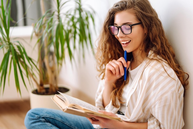 Jeune femme lisant un livre écrivant des notes faisant ses devoirs à la maison Concept de repos relaxation