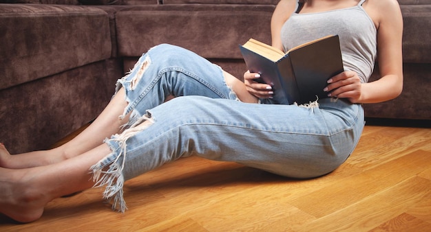 Jeune femme lisant un livre à la maison