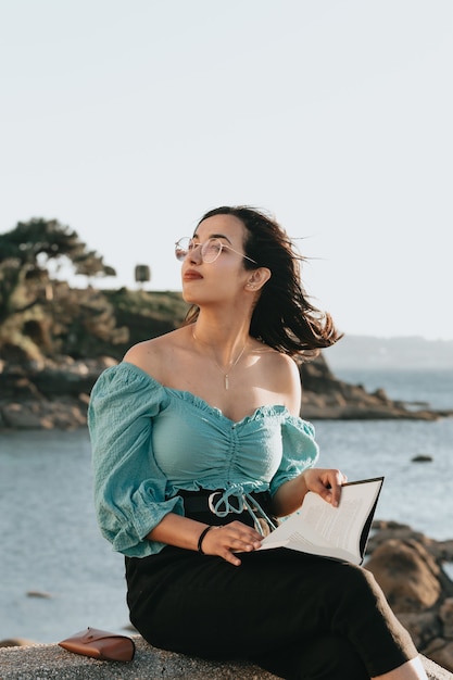 Jeune femme lisant à la plage pendant un super coucher de soleil