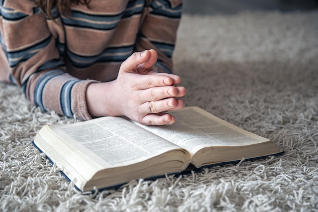 Une jeune femme lit la bible allongée sur le sol