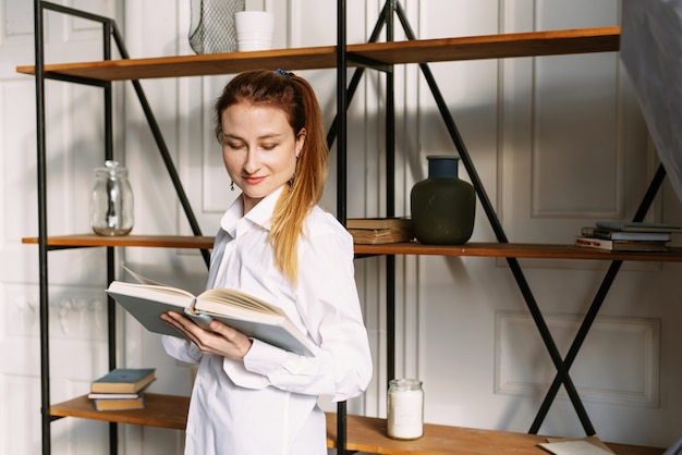 jeune femme lit un livre devant une bibliothèque élégante