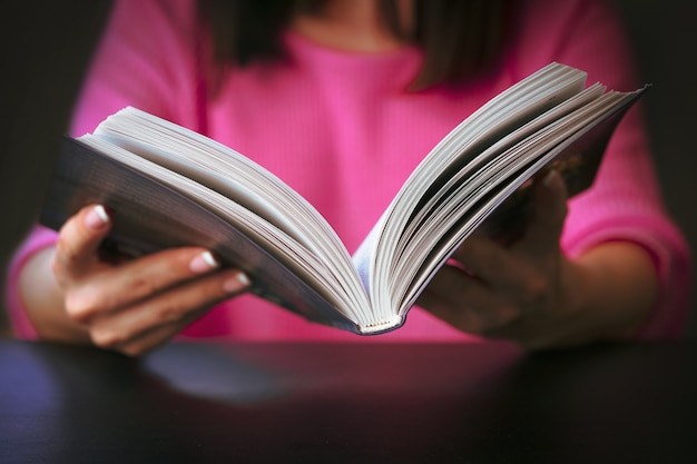 Jeune femme lit un livre à la maison.