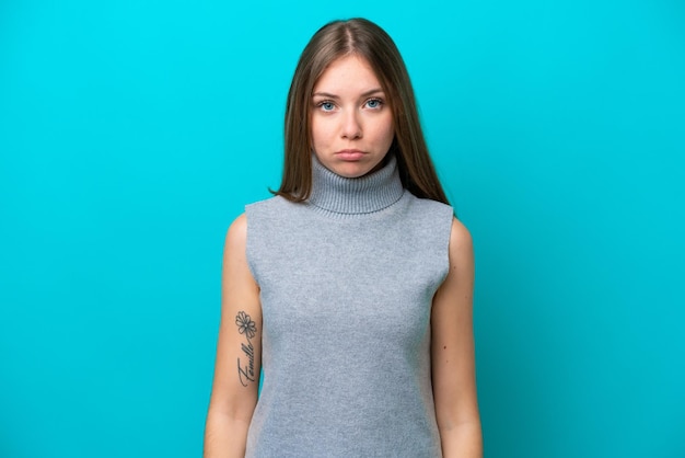 Jeune femme lituanienne isolée sur fond bleu avec une expression triste