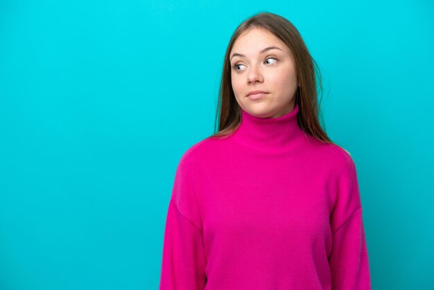 Jeune femme lituanienne isolée sur fond bleu faisant des doutes geste regardant côté