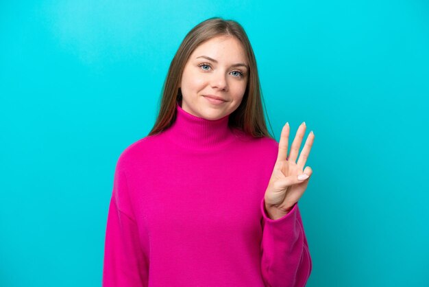 Jeune femme lituanienne isolée sur fond bleu heureuse et comptant trois avec les doigts