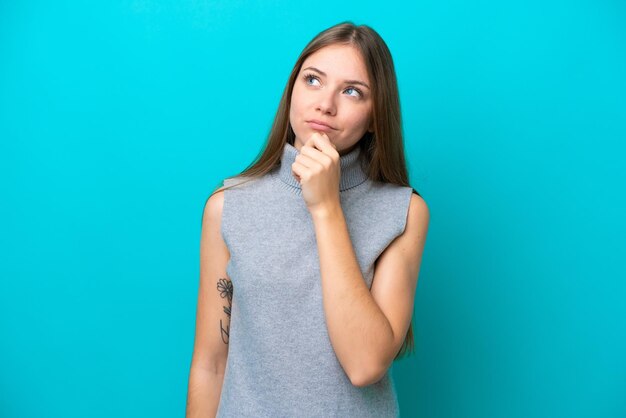 Jeune femme lituanienne isolée sur fond bleu et levant les yeux