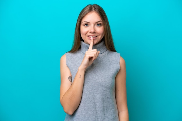 Jeune femme lituanienne isolée sur fond bleu montrant un signe de geste de silence mettant le doigt dans la bouche