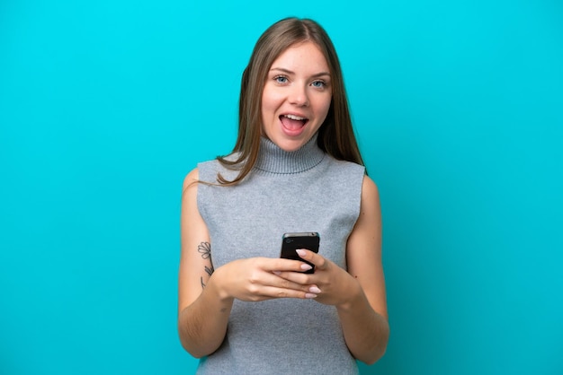 Jeune femme lituanienne isolée sur fond bleu surprise et envoyant un message