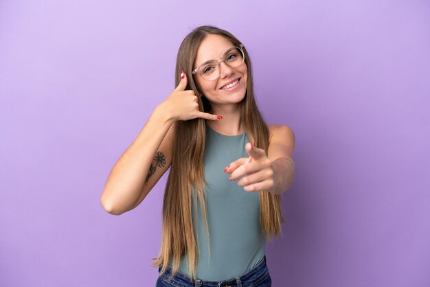 Jeune femme lituanienne isolée sur fond violet faisant un geste de téléphone et pointant vers l'avant