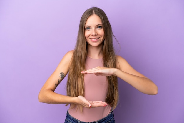 Jeune femme lituanienne isolée sur fond violet tenant un fond imaginaire sur la paume pour insérer une annonce