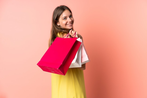 Jeune femme lituanienne isolée sur mur rose tenant des sacs à provisions et souriant