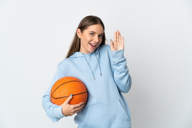 Jeune femme lituanienne jouant au basket isolé sur mur blanc saluant avec la main avec une expression heureuse