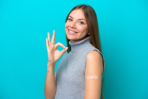 Jeune femme lituanienne portant des pansements isolés sur fond bleu montrant un signe ok avec les doigts