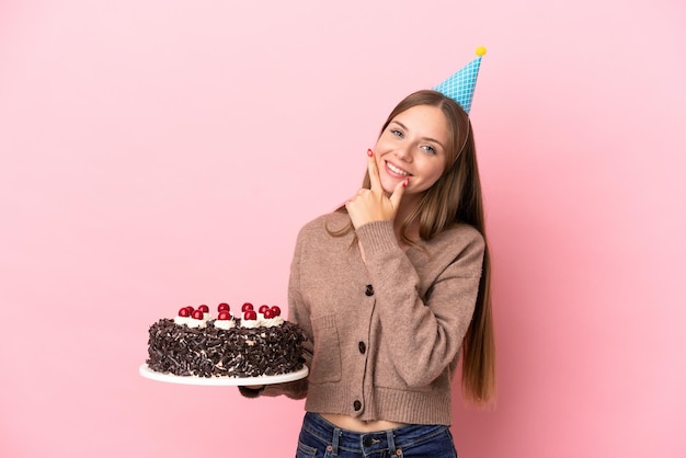 Jeune femme lituanienne tenant un gâteau d'anniversaire isolé sur fond rose heureux et souriant