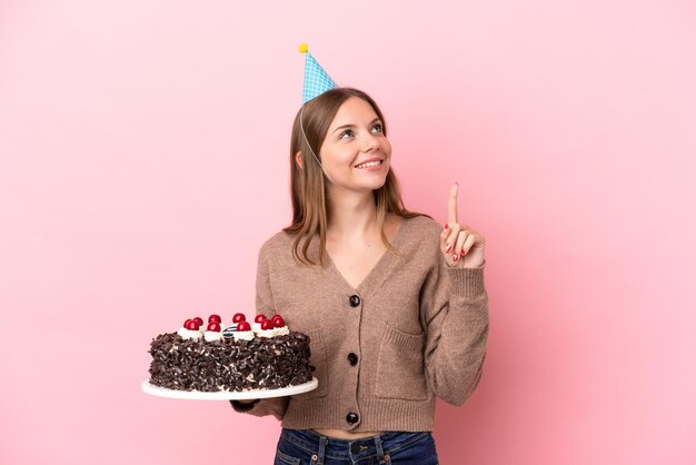 Jeune femme lituanienne tenant un gâteau d'anniversaire isolé sur fond rose pointant vers une excellente idée