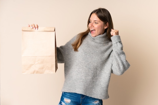 Jeune femme lituanienne tenant un sac d'épicerie célébrant une victoire