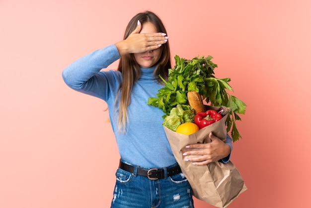 Jeune femme lituanienne tenant un sac d'épicerie couvrant les yeux par les mains. Je ne veux pas voir quelque chose