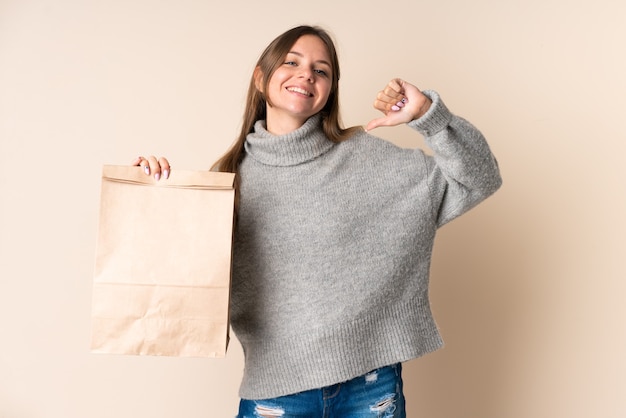 Jeune femme lituanienne tenant un sac d'épicerie fier et satisfait de soi