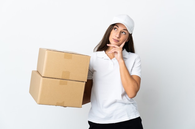 Jeune femme de livraison sur fond blanc isolé en pensant à une idée tout en levant les yeux