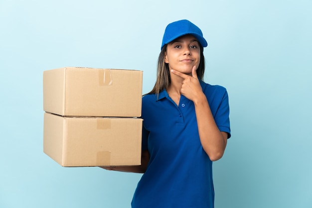 Jeune femme de livraison isolée sur la pensée de mur bleu