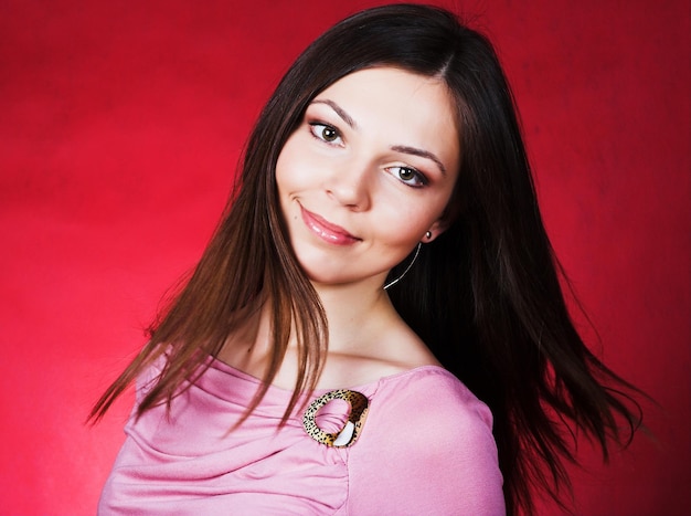 jeune femme, à, longs cheveux, poser, à, studio, sur, arrière-plan rouge, beauté, mode