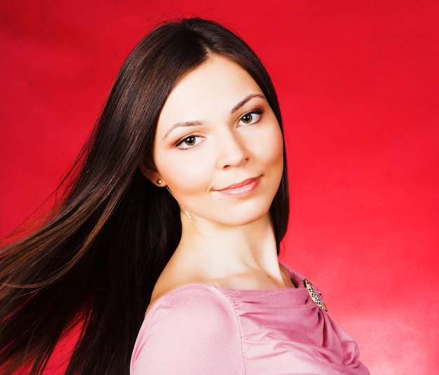 jeune femme, à, longs cheveux, poser, à, studio, sur, arrière-plan rouge, beauté, mode