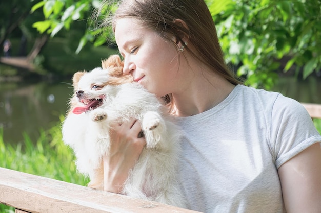 Jeune femme avec de longs cheveux raides et un petit chien moelleux pour une promenade