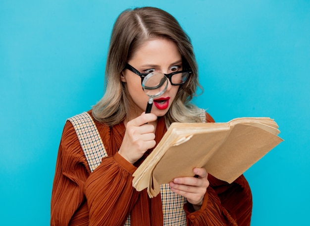 Jeune femme, à, loupe, et, livres, sur, bleu