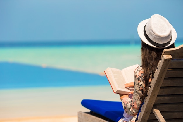 Jeune femme a lu un livre près de la piscine