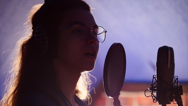 Une jeune femme à lunettes chantant en studio