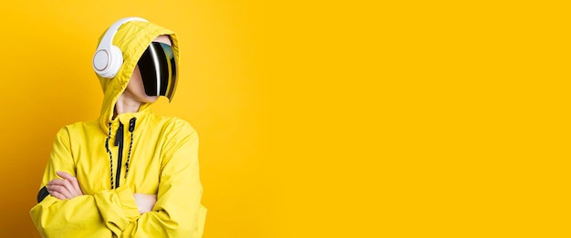 Jeune femme à lunettes cyberpunk avec un casque dans une veste jaune sur fond jaune Bannière