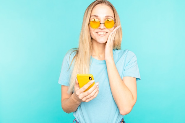 Jeune femme à lunettes debout sur bleu isolé en regardant la caméra.