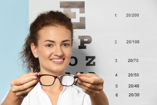 Jeune femme avec des lunettes sur fond de tableau de test de la vue