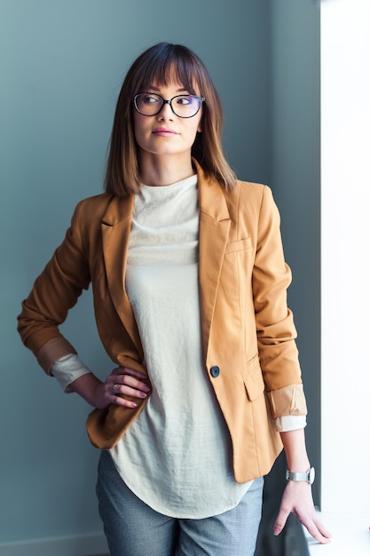 jeune femme à lunettes, habillé comme décontracté sur gris