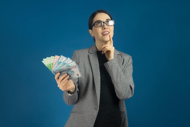 Une jeune femme à lunettes avec un paquet de tenge à la main pense à faire du shopping