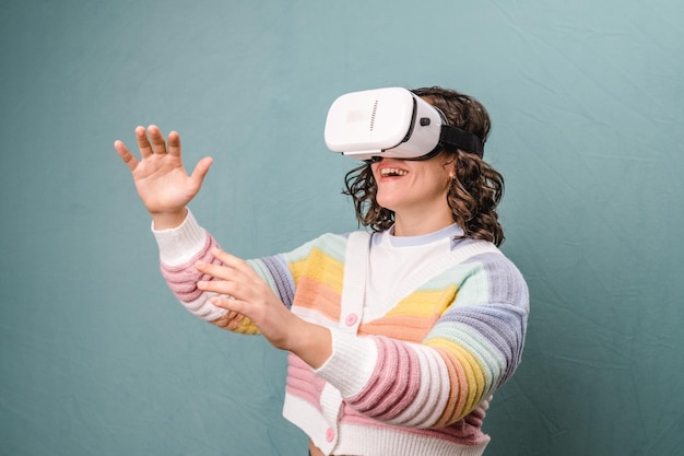 Jeune femme avec des lunettes de réalité virtuelle avec enthousiasme sur fond bleu