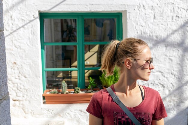Une jeune femme à lunettes regarde par la fenêtre du printemps