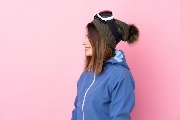 Jeune femme avec des lunettes de ski sur un mur rose