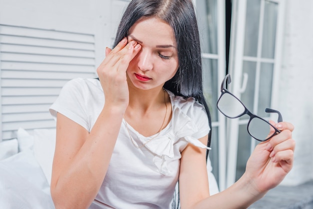 Jeune femme, lunettes, toucher, elle, yeux, à, main