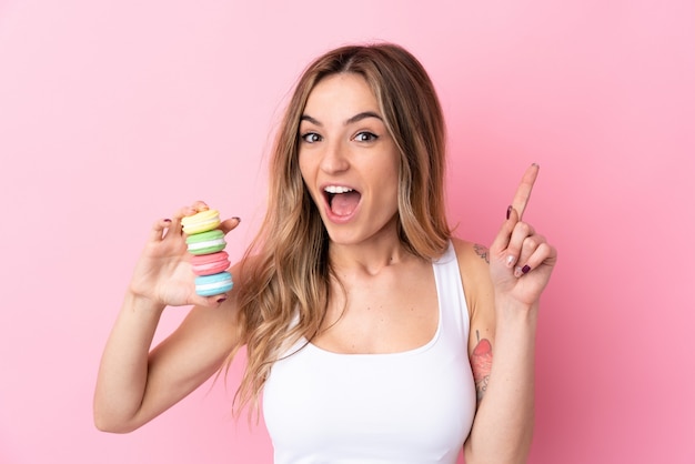 Jeune femme avec des macarons pointant vers le haut une excellente idée