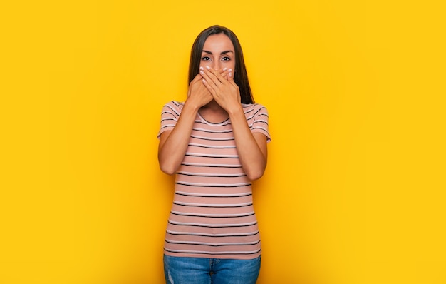 Une jeune femme magnifique se couvre la bouche et regarde la caméra