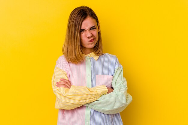 Jeune femme maigre caucasienne isolée sur jaune malheureux regardant à l'avant avec une expression sarcastique.