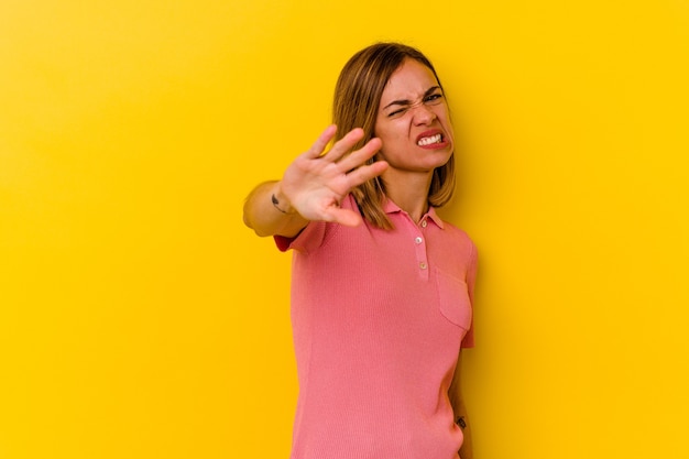 Jeune femme maigre caucasienne isolée sur jaune rejetant quelqu'un montrant un geste de dégoût.